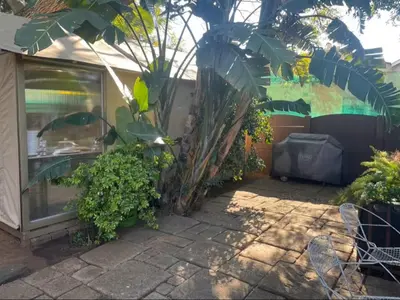 a patio with a bunch of plants and a building at African Paradise - Garden Glamping - Outdoor Shower in Benoni