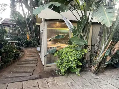 a building with a glass door in a garden at African Paradise - Garden Glamping - Outdoor Shower in Benoni