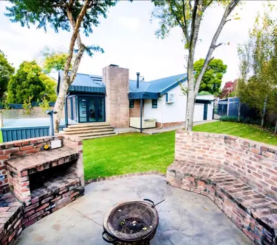 a backyard with a brick fire pit and a house at Rusgerus in Pretoria