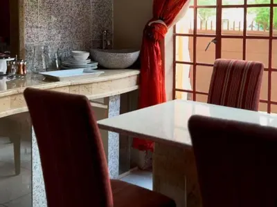 a dining room with a table and chairs and a sink at Wonder House Lodge in Mokopane