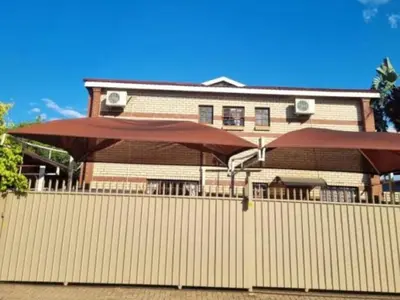 a building with a fence and a large umbrella at Wonder House Lodge in Mokopane