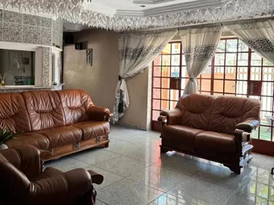 a living room with two leather couches and windows at Wonder House Lodge in Mokopane
