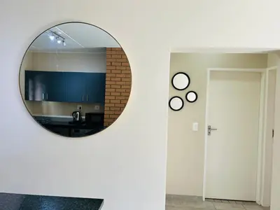 a round mirror on a wall in a room at Stunning modern 2 bedroom apartment in Waterfall Ridge in Midrand