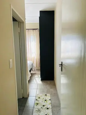 a hallway with a black door and a rug at Stunning modern 2 bedroom apartment in Waterfall Ridge in Midrand