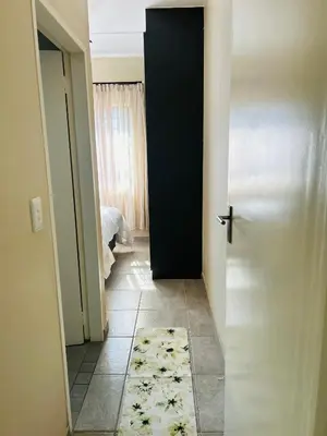 a hallway with a door and a rug on the floor at Stunning modern 2 bedroom apartment in Waterfall Ridge in Midrand