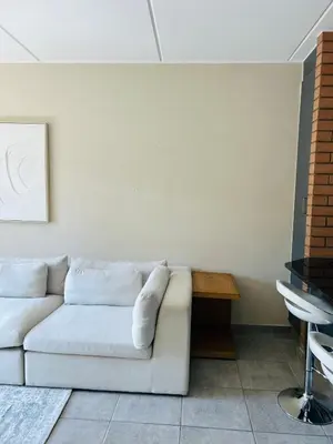 a living room with a white couch and a table at Stunning modern 2 bedroom apartment in Waterfall Ridge in Midrand