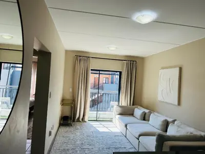 a living room with a couch and a window at Stunning modern 2 bedroom apartment in Waterfall Ridge in Midrand