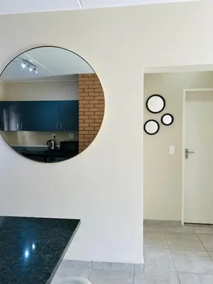 a circular mirror on a wall in a room at Stunning modern 2 bedroom apartment in Waterfall Ridge in Midrand