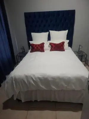 a large white bed with two red pillows on it at 77 Pendleberry Grove in Warmbaths