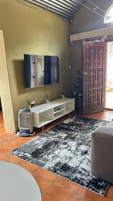 a living room with a tv and a white couch at Garden Unit in Pretoria