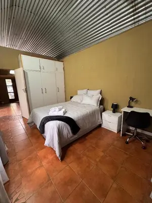 a bedroom with a bed and a desk at Garden Unit in Pretoria