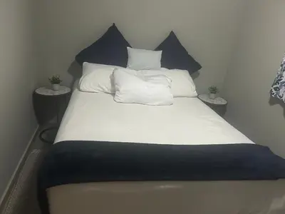 a bed with blue and white sheets and pillows at Double Bed in the Capital City in Pretoria