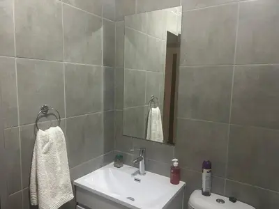 a bathroom with a sink and a toilet and a mirror at Double Bed in the Capital City in Pretoria