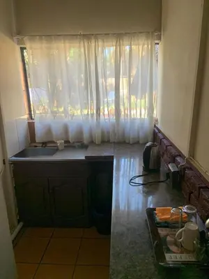 a kitchen with a sink and a window with curtains at Epizone in Mokopane