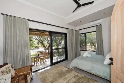 a bedroom with a bed and a large window at River Retreat in Malelane