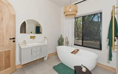 a bathroom with a tub and a sink and a mirror at River Retreat in Malelane