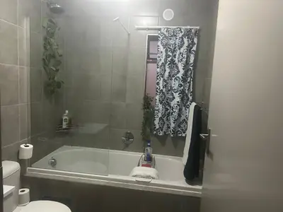 a bathroom with a bath tub and a toilet at Two Bedrooms in the Capital City in Pretoria