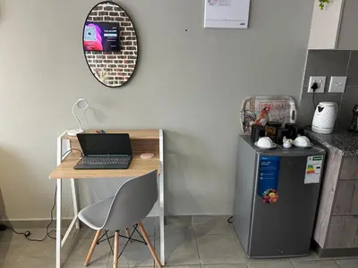 a table and a desk with a laptop on top of a refrigerator at Two Bedrooms in the Capital City in Pretoria