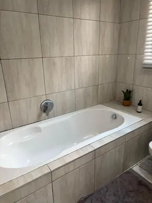 a white bath tub in a bathroom with a plant at Lulu's guest house in Nelspruit