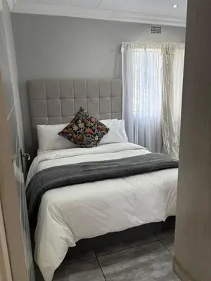 a bedroom with a large bed and a window at Lulu's guest house in Nelspruit