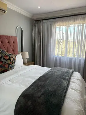 a bedroom with a large bed and a window at Lulu's guest house in Nelspruit
