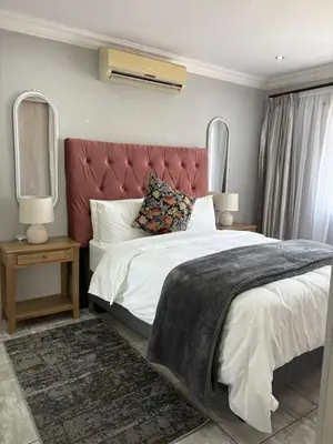 a bedroom with a large bed with a red headboard at Lulu's guest house in Nelspruit