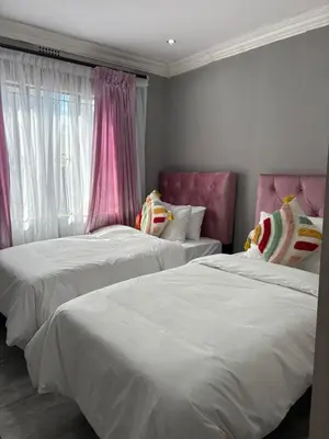 two beds in a room with pink and white at Lulu's guest house in Nelspruit