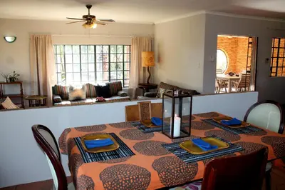 a dining room with a table and a living room at Ndlovu 41 inside the Dinokeng Big 5 Game Reserve in Dinokeng Game Reserve