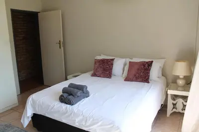 a white bed with a stuffed elephant on it at Ndlovu 41 inside the Dinokeng Big 5 Game Reserve in Dinokeng Game Reserve