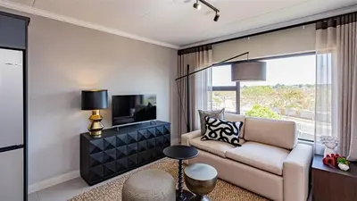 a living room with a couch and a tv at Aesthetic modern apartment in Midrand