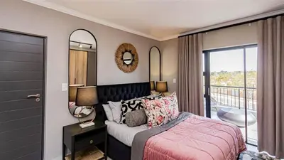 a bedroom with a bed and a balcony at Aesthetic modern apartment in Midrand