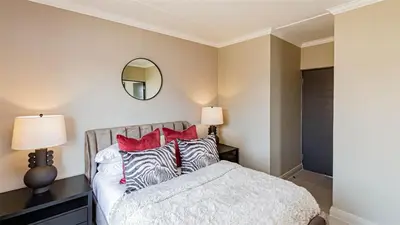 a bedroom with a bed with red pillows and a mirror at Aesthetic modern apartment in Midrand
