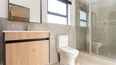 a bathroom with a toilet and a sink and a shower at Aesthetic modern apartment in Midrand