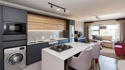 a kitchen with a stove top oven next to a living room at Aesthetic modern apartment in Midrand