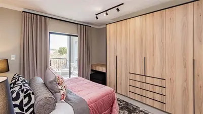 a bedroom with a bed and a sliding glass door at Aesthetic modern apartment in Midrand