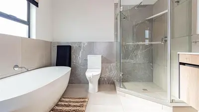 a bathroom with a tub and a toilet and a shower at Aesthetic modern apartment in Midrand