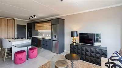 a kitchen with pink stools and a kitchen with a counter at Aesthetic modern apartment in Midrand