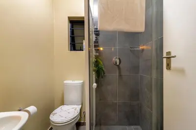 a bathroom with a shower with a toilet and a sink at The Local house in Midrand