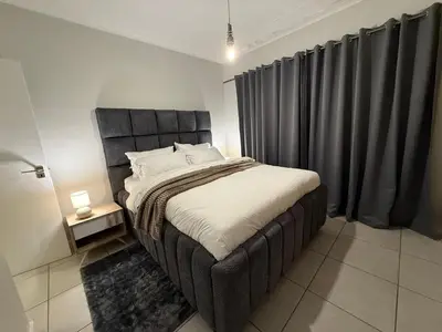 a bedroom with a large bed with black curtains at The Dream Stay At The Blyde - Suite 1 in Pretoria