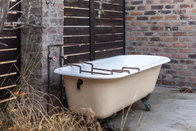 an old bath tub sitting next to a brick wall at Thuhlo in Marloth Park