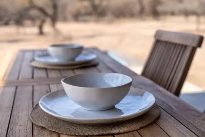a wooden table with two cups and plates on it at Thuhlo in Marloth Park