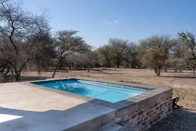 a swimming pool in a brick wall in a field at Thuhlo in Marloth Park