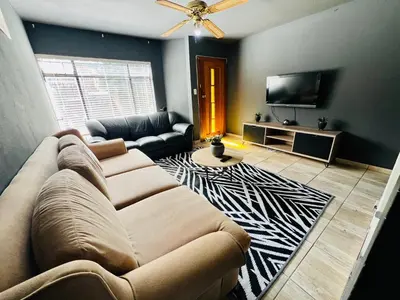 a living room with a couch and a flat screen tv at Grey Villa on Orion- Luxury Apartment in Polokwane