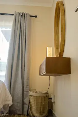 a mirror and a lamp in a room with a curtain at Kamotha Guest House