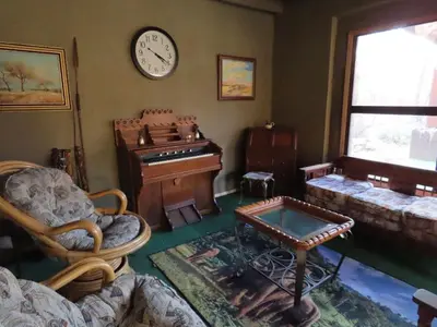 a living room with a piano and a clock on the wall at Unique Kruger Hide & Spa in Marloth Park