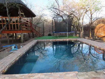 a swimming pool with a swing and a tree house at Unique Kruger Hide & Spa in Marloth Park