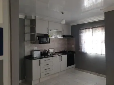 a kitchen with white cabinets and a black appliances at Cuse guest house in Polokwane