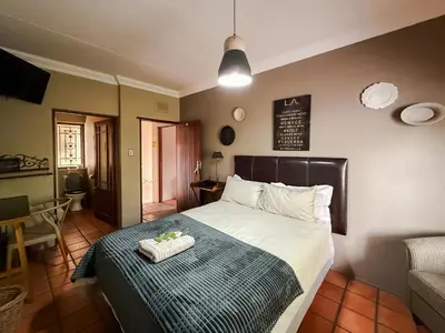 a bedroom with a bed with a green and white blanket at The Urn Guesthouse in Middelburg
