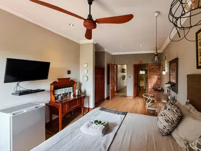 a living room with a bed and a ceiling fan at The Urn Guesthouse in Middelburg