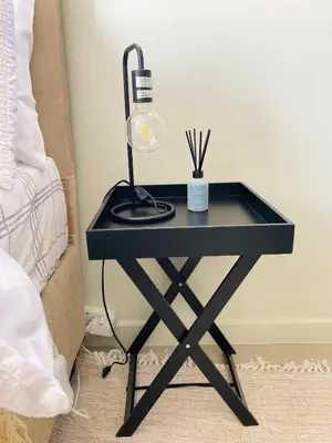 a black table with a lamp on it next to a bed at The Minimalist Hideout in Midrand
